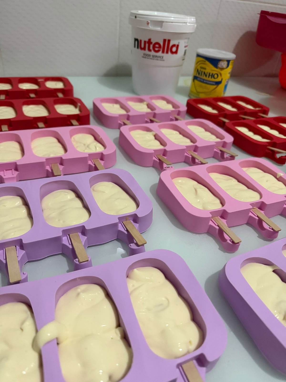 Picolés recheados sendo preparados nas forminhas